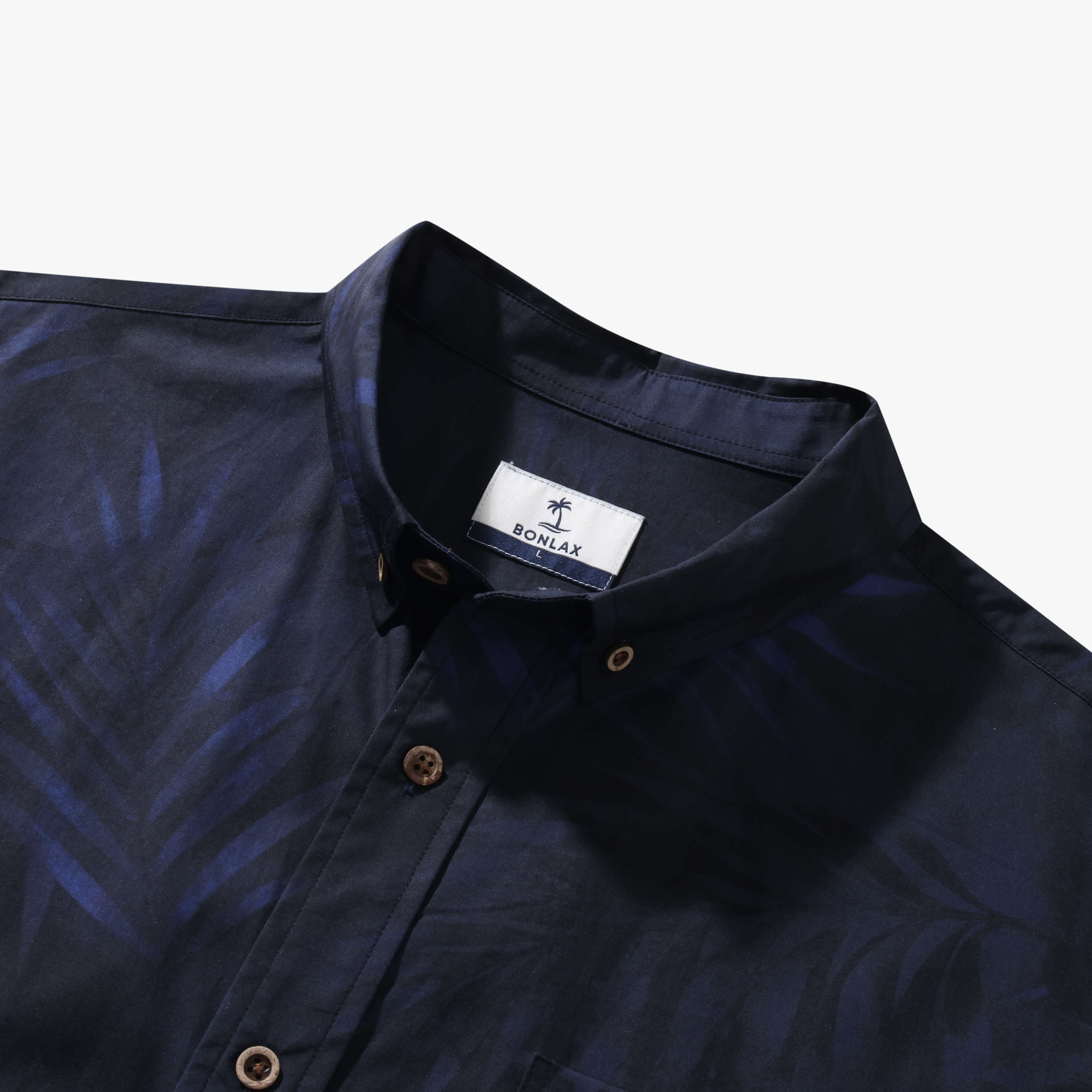 Close-up of the ink blue Shadow Palm shirt collar, coconut buttons and tone-on-tone tropical print