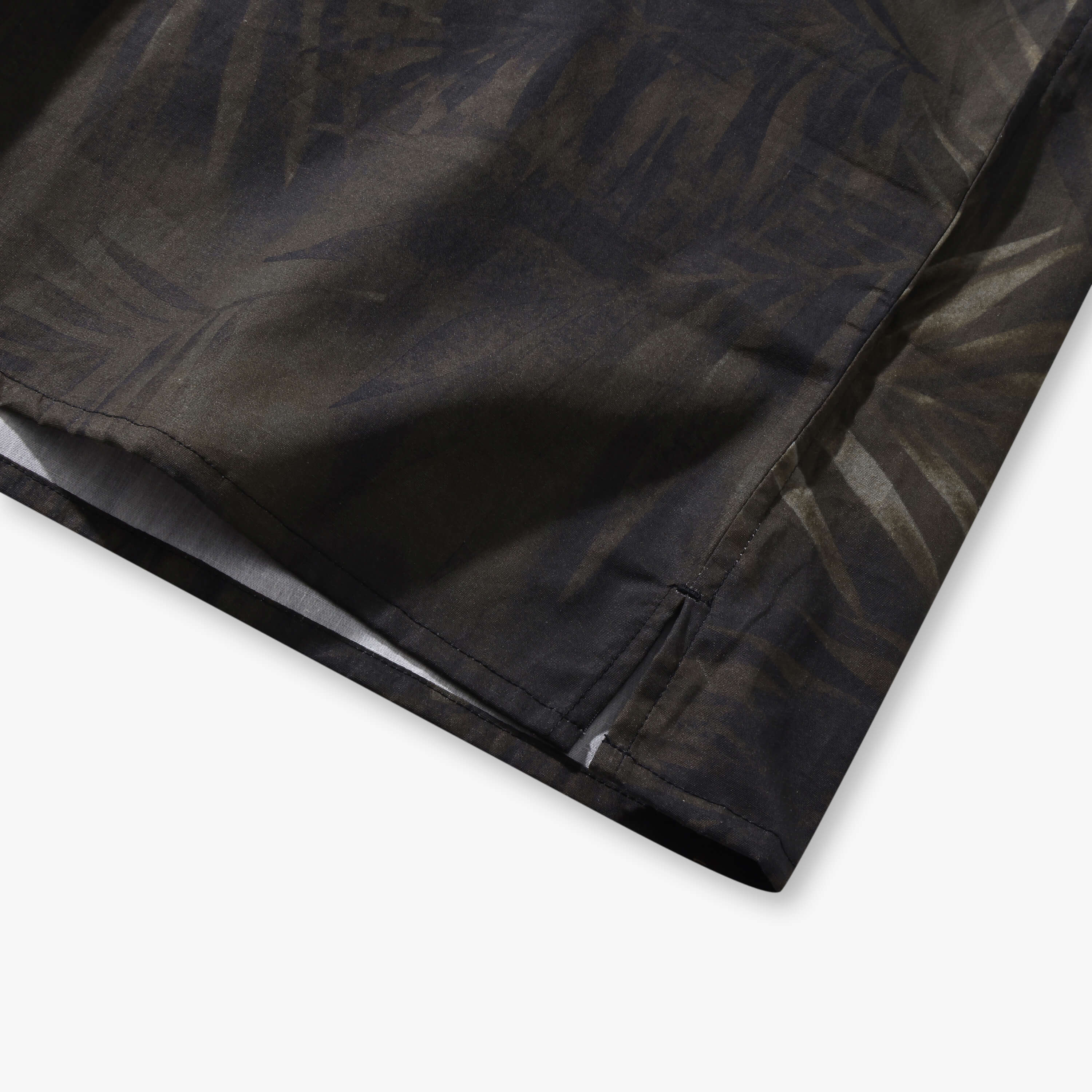Close-up of the sage green Shadow Palm shirt side vent and straight hem