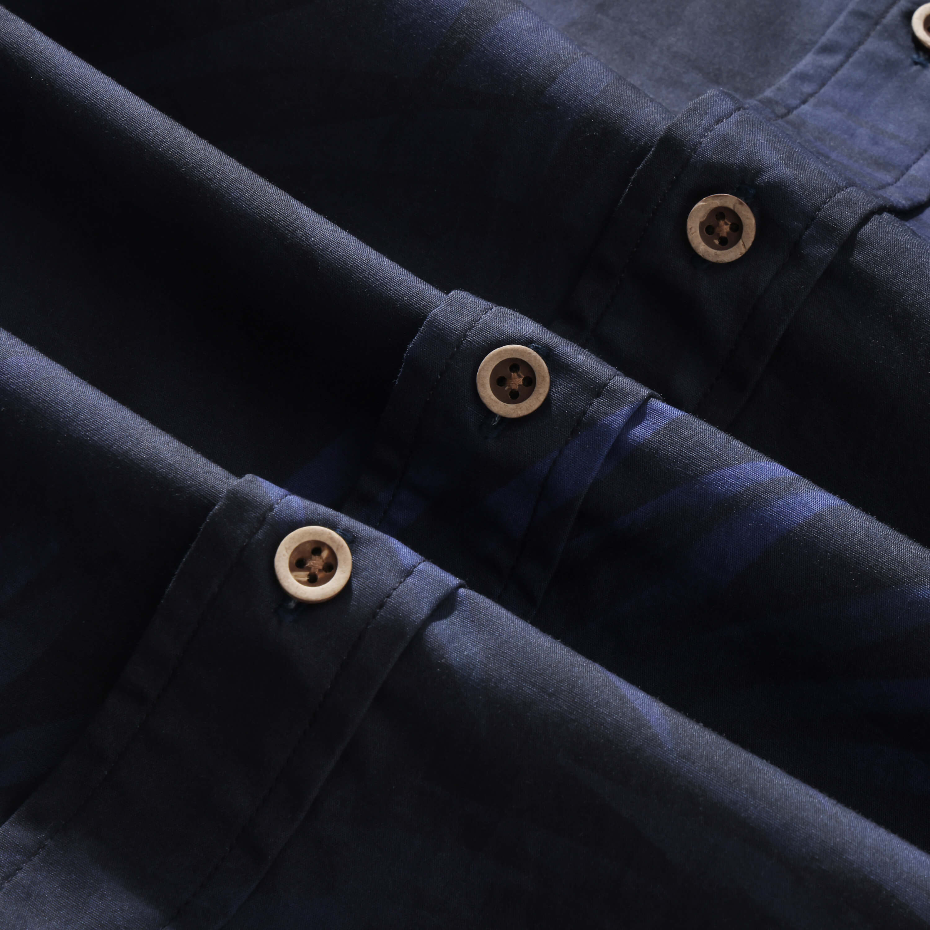 Close-up of coconut buttons on the ink blue Shadow Palm shirt placket