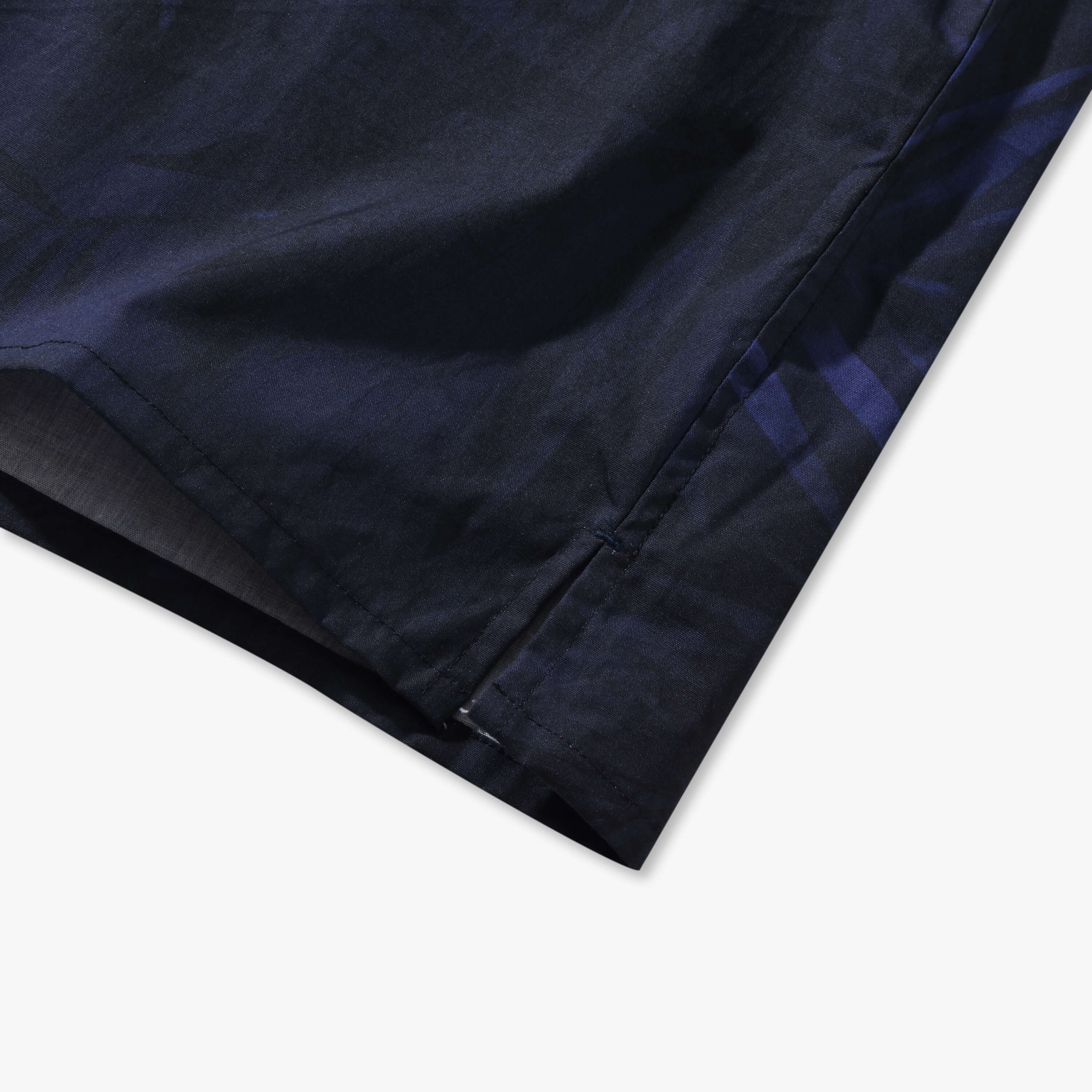 Close-up of the ink blue Shadow Palm shirt side vent, straight hem and reinforced stitching